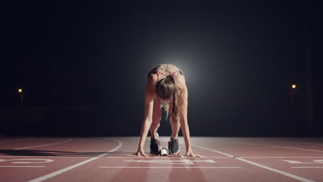 Una-Mujer-En-La-Oscuridad-Del-Estadio-Se-Prepara-Para-Iniciar-Una-Carrera-En-La-Pista.-Mujer-En-Cámara-Lenta-Comienza-Una-Huelga-De-Hambre-En-El-Estadio-En-La-Oscuridad